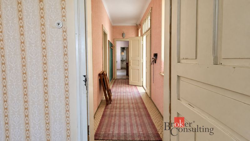 A hallway with patterned wallpaper and carpet in a family house.