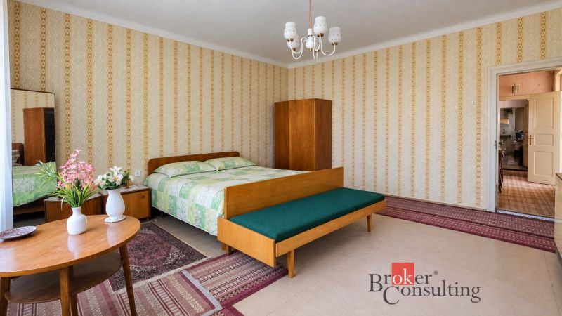 A spacious bedroom with retro furniture, wallpaper, and flowers in a family house.