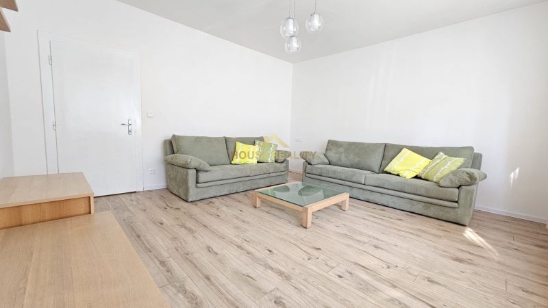 Living room with green sofas, a glass table, and a wooden decor floor.