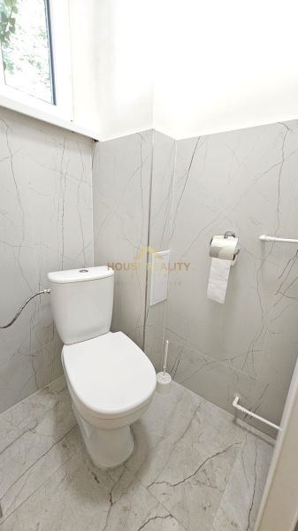 A bathroom in a 2-room apartment with marble tiles and a toilet.