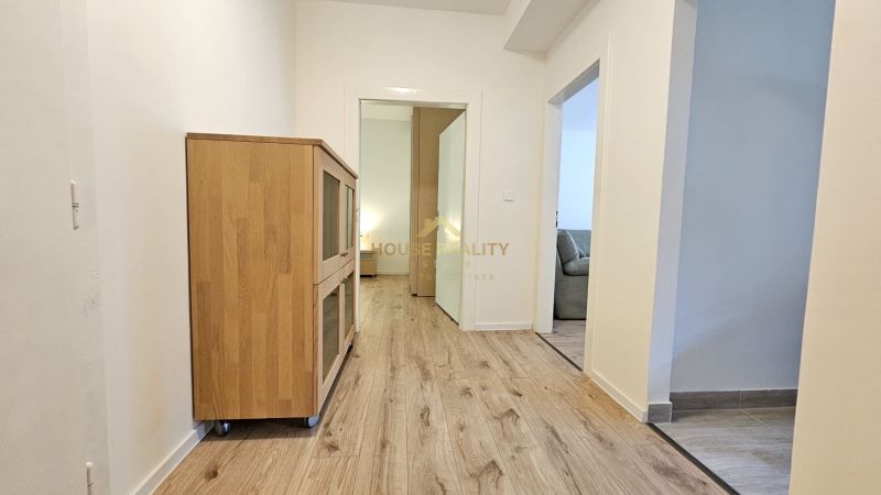 A hallway in a 2-room apartment with a wooden decor floor and a cabinet on wheels.
