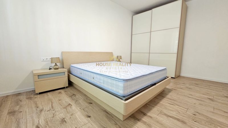 Bedroom with a bed, nightstand, storage wardrobe, and wooden decor flooring in a 2-room apartment.
