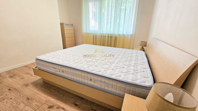 Bedroom in a two-room apartment with a bed and a wooden decor floor.