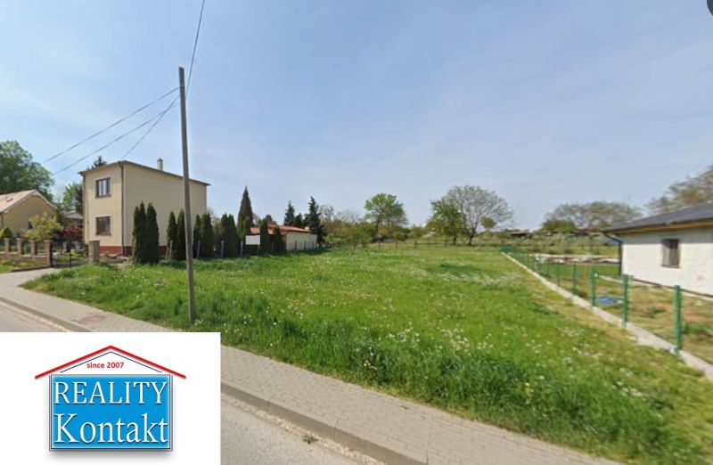 A green residential plot in the village of Bardoňovo, bordered by family houses.