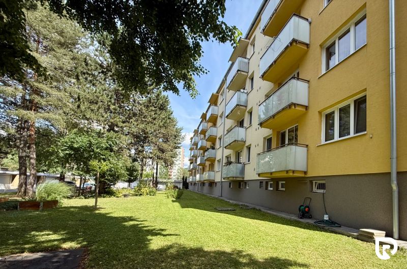 An apartment building on Pred poľom Street in Trenčín, surrounded by greenery and trees.