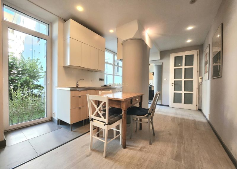 A kitchen in a 2-room apartment with a table and a floor with a wooden decor.