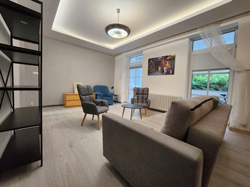 Living room in a two-room apartment with comfortable armchairs, a sofa, and a floor with a wooden decor.