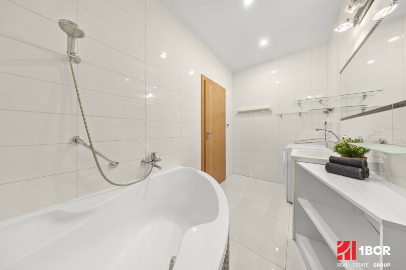 Bathroom with a bathtub, white tiles, a sink, and wooden doors in a 3-room apartment.