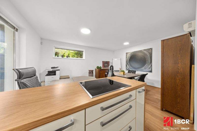 A room with a wooden decor floor, office equipment, and a view of greenery.