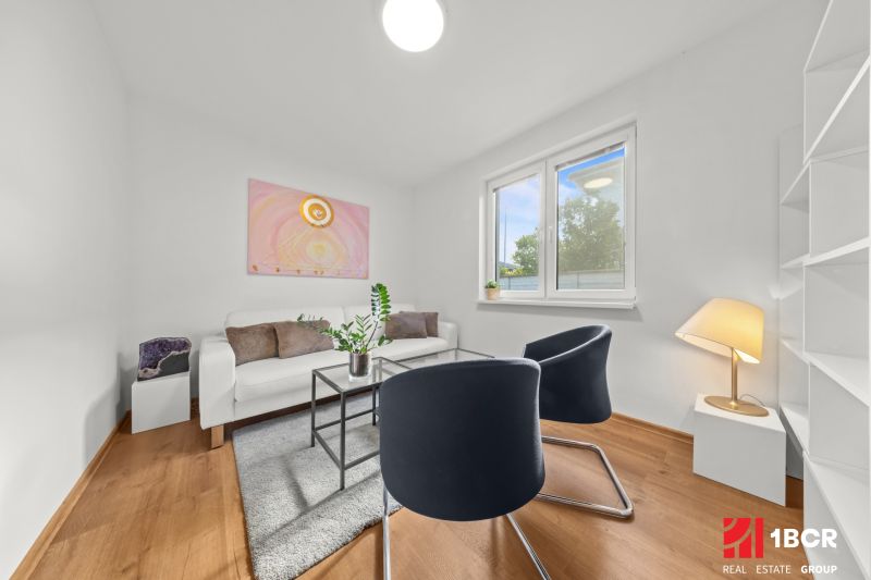 Living room in a 3-room apartment with a wooden decor floor, modern armchairs, and decorations.