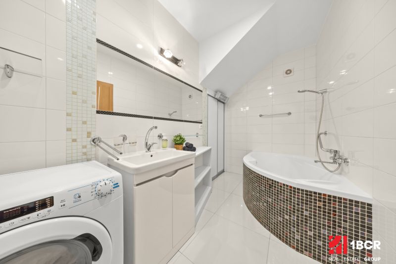 A bathroom with a bathtub in a 3-room apartment complemented by a washing machine and a sink.