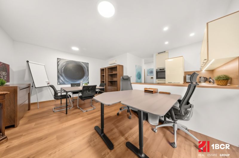 An office with desks, chairs, and a floor with a wood decor in a 3-room apartment.