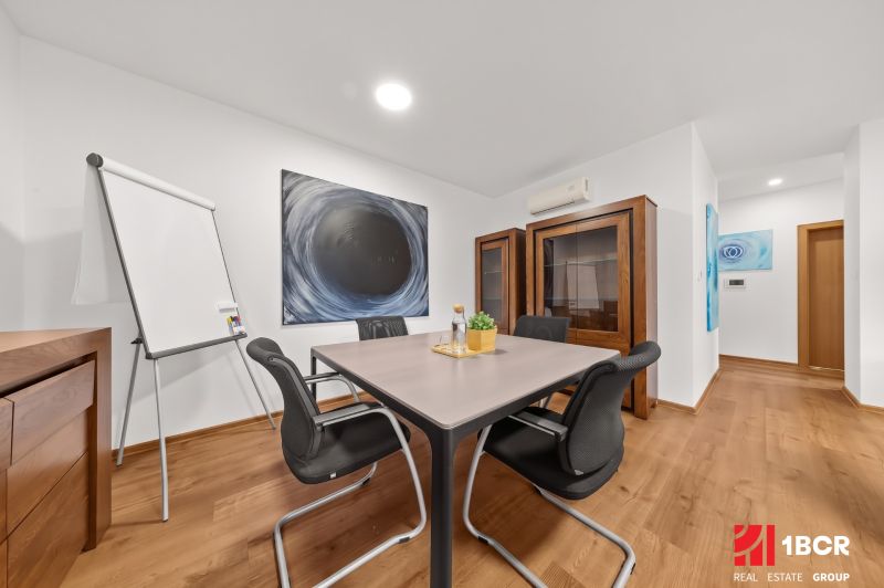 Part of a 3-room apartment with a table, chairs, wooden decor, and artwork on the wall.