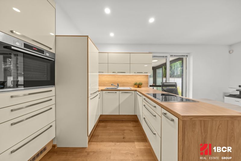 A kitchen with modern white cabinets, wooden floor decor, and a dining nook.