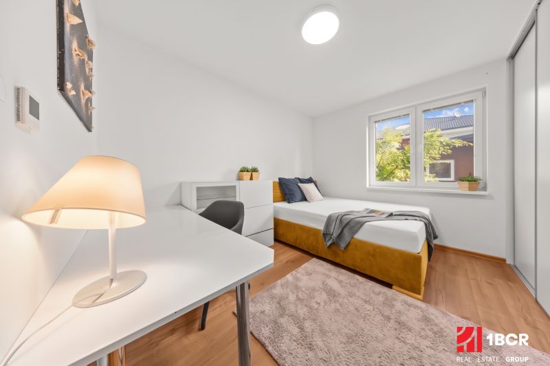 A bright room in a 3-room apartment with a bed, a table, and a wooden-decor floor.