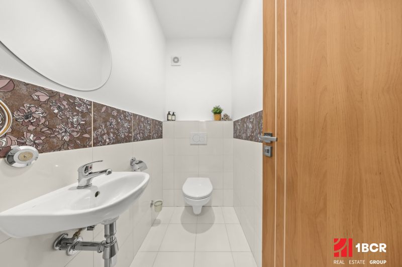 A bathroom with floral tiles and a wall mirror in a 3-room apartment.