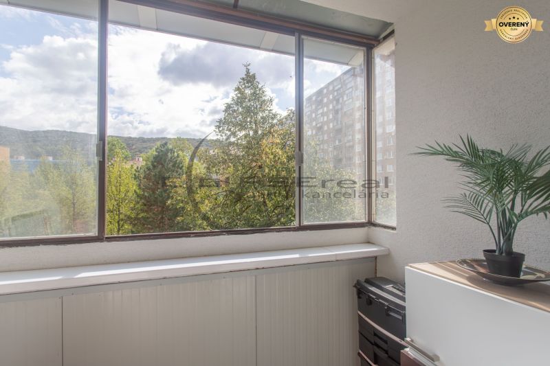 A glazed balcony with a view of greenery and a block of flats in Bratislava - Devínska Nová Ves.