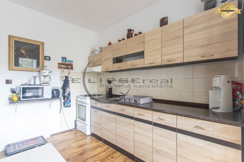 A kitchen in a 3-room apartment with a wooden floor decor and light cabinets.