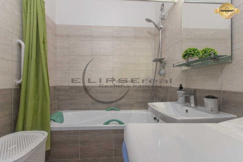 Bathroom in a 3-room apartment with a bathtub, green curtain, and wooden decor tiles.