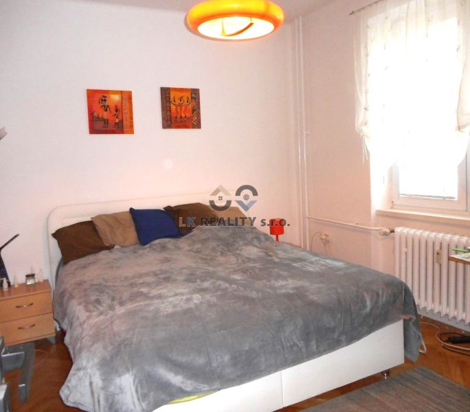 Bedroom in a 2-room apartment with a double bed, nightstands, and a wooden decor floor.