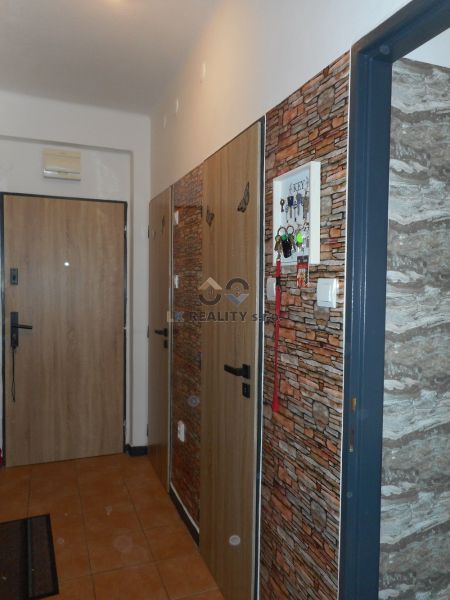 Entrance hallway in a 2-room apartment with tiles and imitation brick wall.
