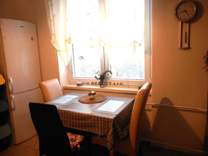 Kitchen in a 2-room apartment with a dining table, chairs, and a refrigerator.
