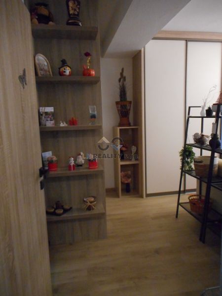 Interior of a 2-room apartment with a wooden decor floor and wooden shelves.
