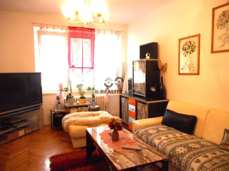 Living room in a two-room apartment with a wooden decor floor and cozy furnishings.