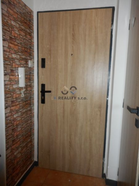 Entrance door with wood decor and stone cladding in a 2-room apartment.