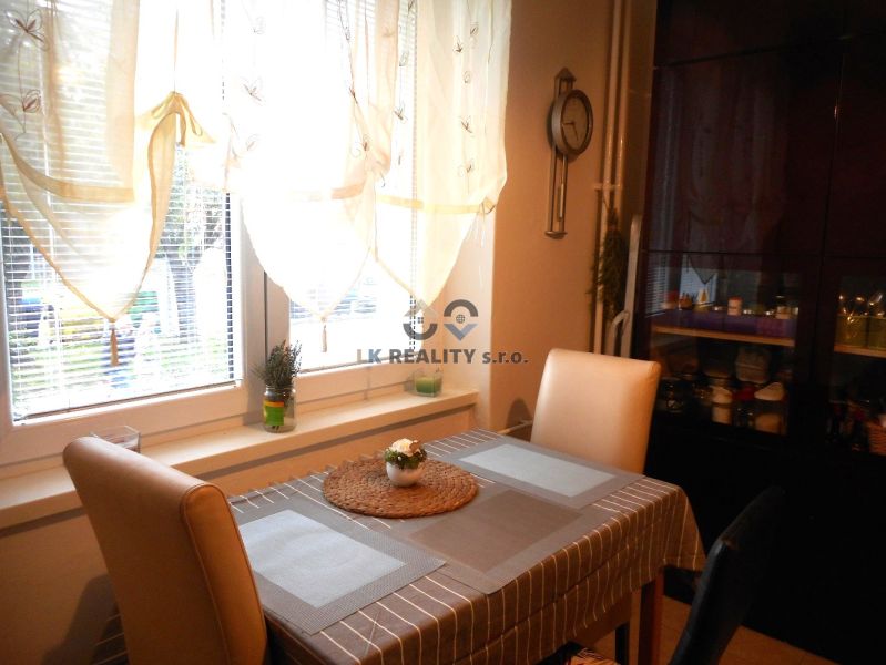 Dining area in a 2-room apartment, with a window and designer curtains, wooden decor.