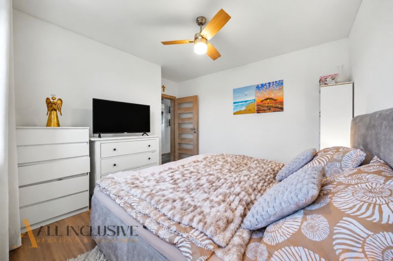 A bedroom in a family house with white furniture, paintings, and decorations.