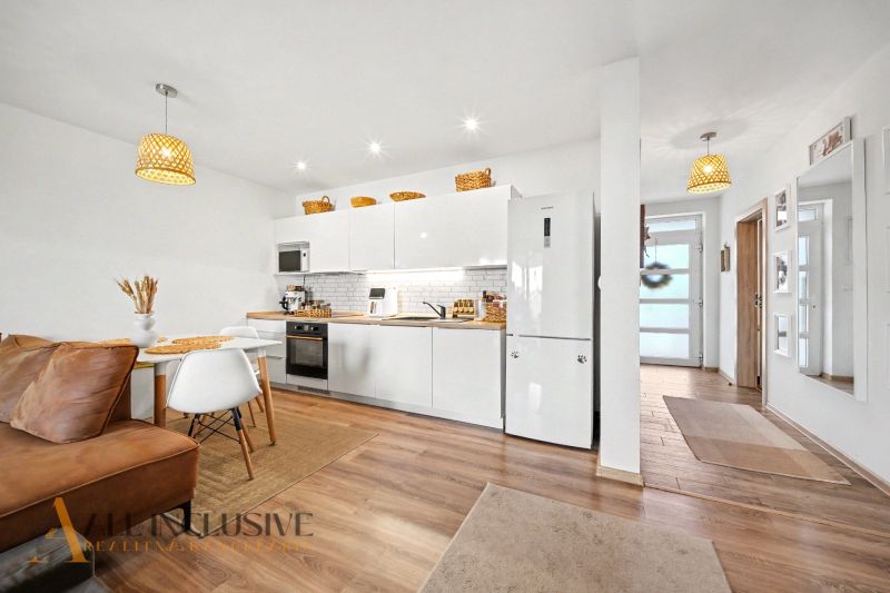 The kitchen and dining room in the family house with a wooden decor floor and white cabinets.