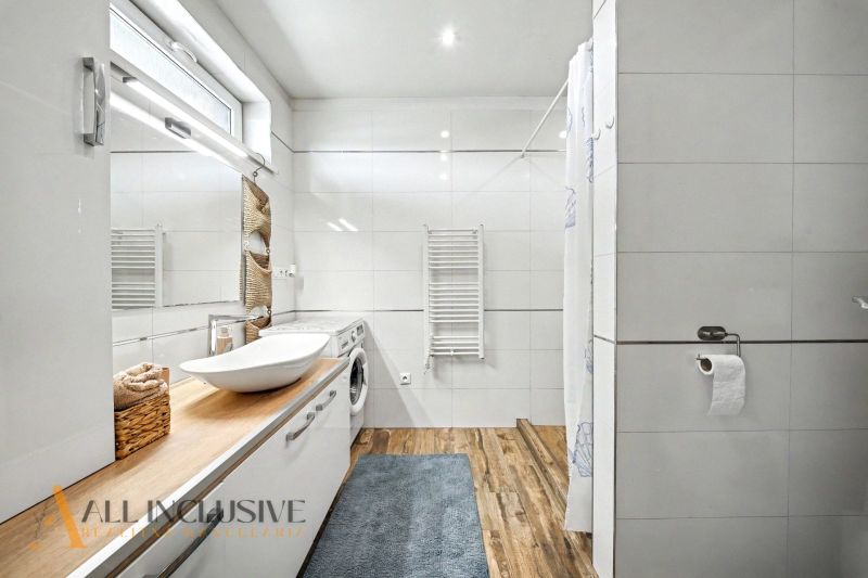 A bathroom in a family house with a modern sink and a floor with a wooden decor.
