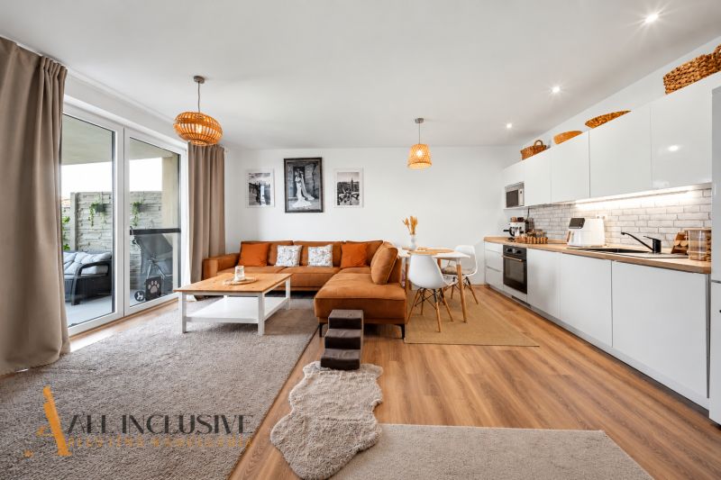 Interior of a family house with a bright kitchen, orange sofa, and a floor with a wooden decor.