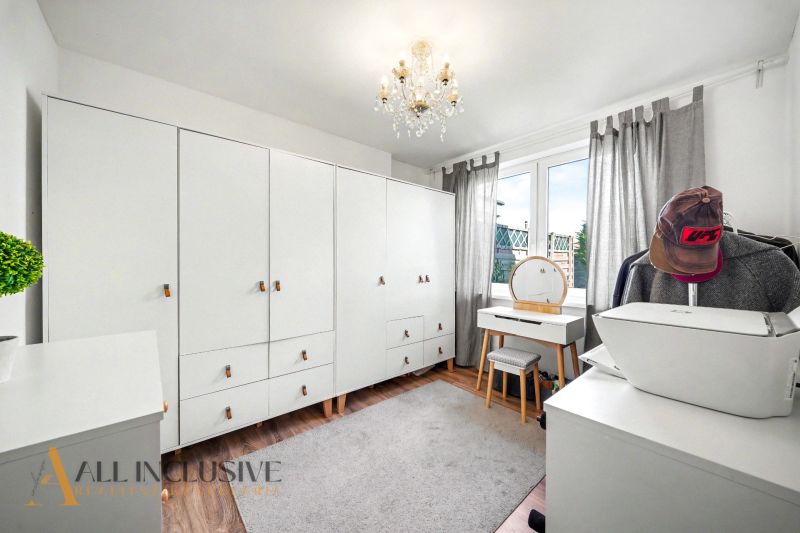 The interior of a family house, a bright room with white cabinets and a floor with a wooden decor.