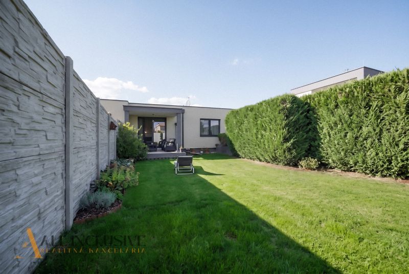 A garden of a family house in Oľdza with a lawn, a hedge, and a terrace for relaxation.