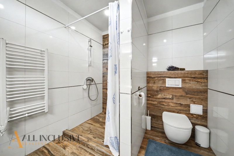 A bathroom in a family house with wood-patterned tiles and a shower enclosure.