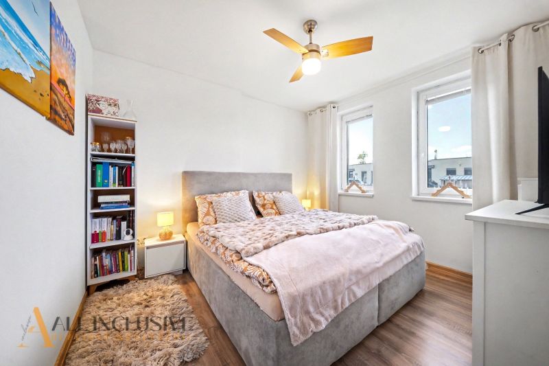 Bedroom in a family house with a bed, bookshelf, and wooden decor flooring.