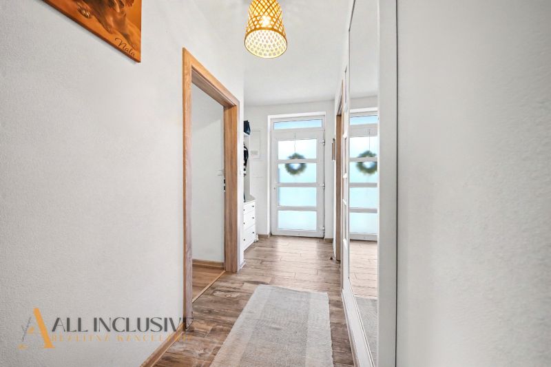 A hallway with a wooden decor floor and large mirrors in a family house.
