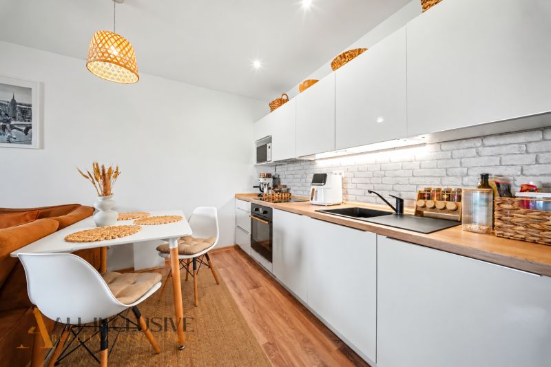 Kitchen with dining area, white cabinets, and wood-patterned flooring.