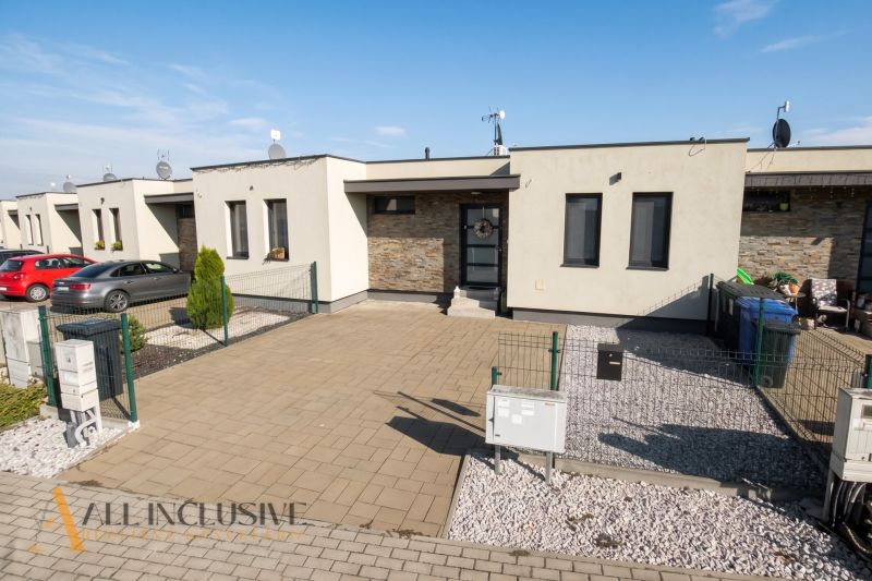 A family house in Oľdza with two cars, a landscaped garden, and paving.