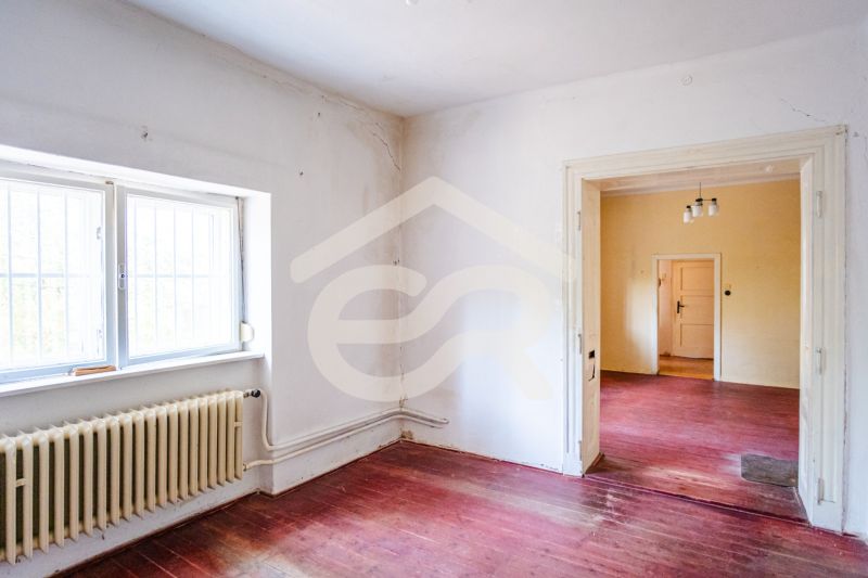 A room in a family house with a window, radiator, and floor with a wooden decor.