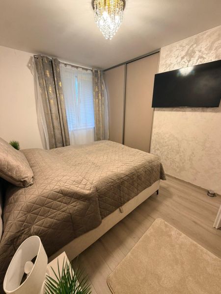 Bedroom in a 3-room apartment with a bed, television, and wood-patterned flooring.
