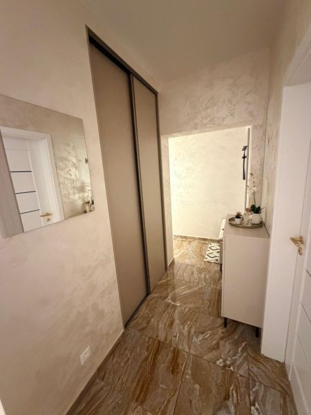 A hallway in a 3-room apartment with glossy tiles, a mirror, and a built-in wardrobe.