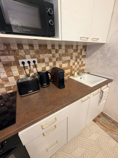 A kitchen in a 3-room apartment with a microwave, kettle, and coffee maker on the countertop.