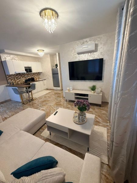 Living room in a 3-room apartment with a TV, sofa, and chandelier.