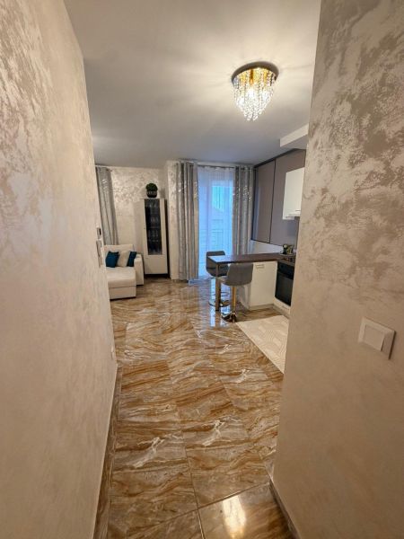 The apartment has shiny tiles, an elegant chandelier, and an open space with seating.