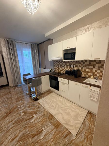 A kitchen in a 3-room apartment with glossy tiles, white cabinets, and a dining area.