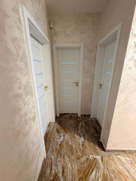 A hallway in a 3-room apartment with a tiled floor and white doors.
