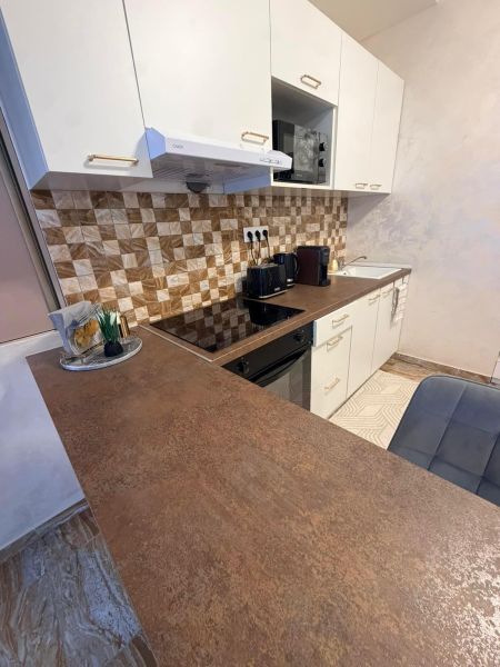 A kitchen in a 3-room apartment with a rustic countertop and tiles with a geometric pattern.